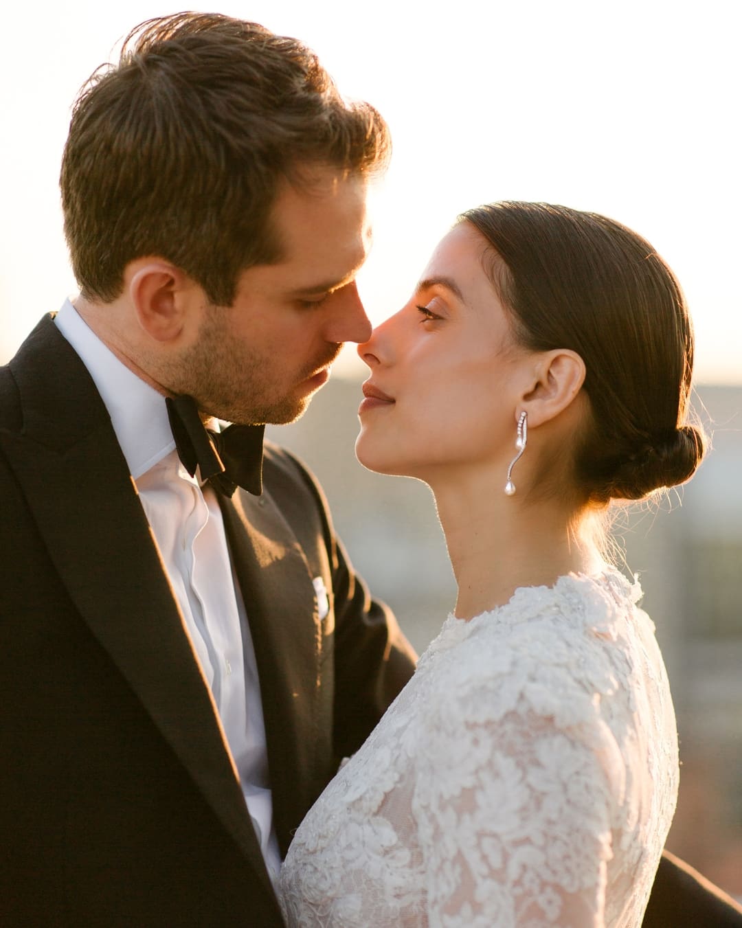 bride in white lace dress and groom in tux captured in the tension of an almost kiss.